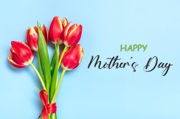 Bukiet czerwonych tulipanów tekst Happy Mother's Day na niebieskim tle