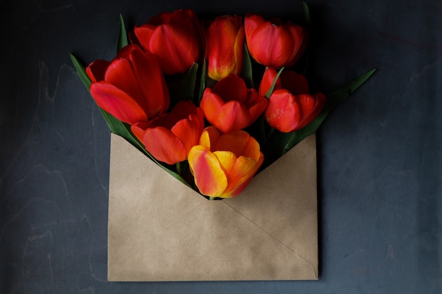 bukiet czerwonych tulipanów w kopercie na ciemnym tle
