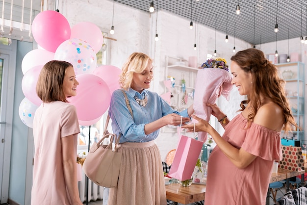 Bukiet I Prezenty. Dwie Piękne Siostry Dają Bukiet I Przedstawiają Swoją Ciężarną Siostrę, świętując Baby Shower