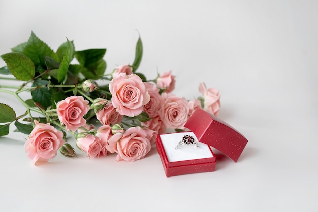 Bukiet Jasnoróżowych Róż I Wysadzany Klejnotami Pierścionek Zaręczynowy W Otwartym Czerwonym Pudełku Z Biżuterią. Obchody Walentynek
