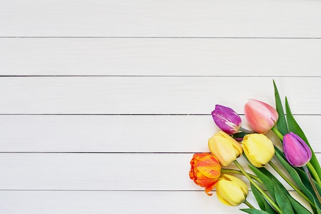 Bukiet kolorowych tulipanów na białym tle drewnianych. Skopiuj miejsce, widok z góry. Dzień matki, urodziny, koncepcja Walentynki. Tło wakacje.