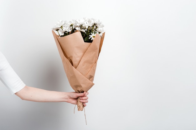 Bukiet Kwiatów Rumianku W żeńskiej Ręce Na Białej ścianie