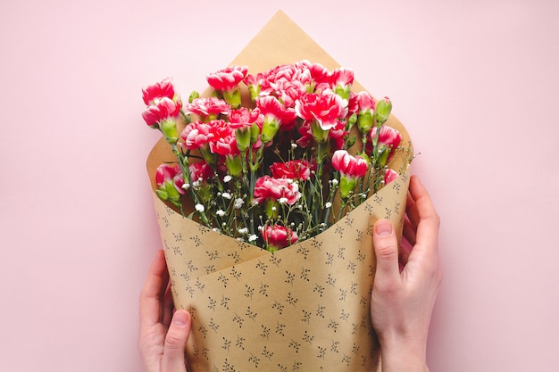 Bukiet kwiatów w rzemiośle papieru na różowym tle. Florystyka Kwiaciarnia z bukietem świeżych goździków.