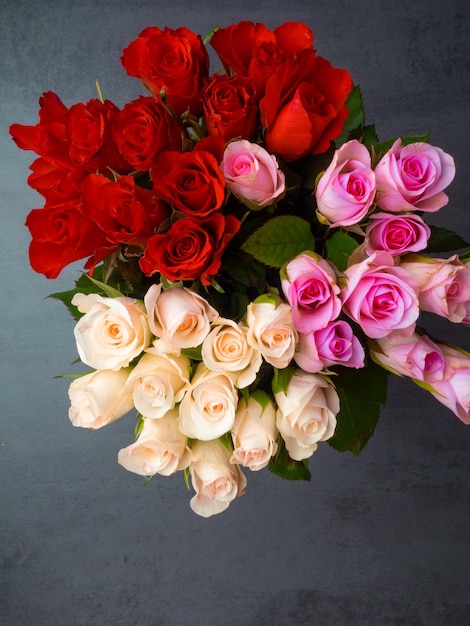 Zdjęcie bukiet otwartych róż w różnych kolorach na szarym betonowym stole