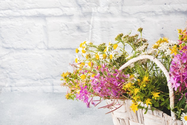 Bukiet piękni wildflowers w koszu na szarej powierzchni z kopii przestrzenią.