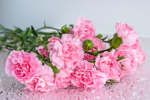 Bukiet różowych kwiatów goździka na stole z kroplami wody