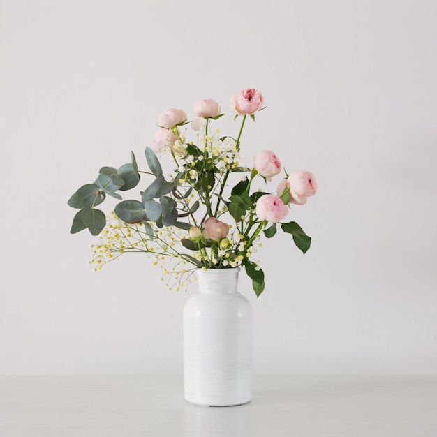 Bukiet różowych róż w ceramicznym białym wazonie na białym tle