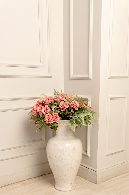 Bukiet różowych róż w ceramicznym wazonie podłogowym w klasycznym stylu. Shbby szykowna dekoracja wnętrz.