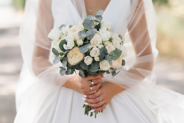 Bukiet ślubny w pastelowych kolorach w rękach panny młodej róż eustoma piwonie goździki i eukaliptus