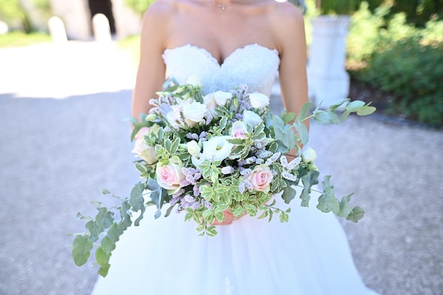 Zdjęcie bukiet ślubny w rękach panny młodej. panna młoda w klasycznej białej koronkowej sukience trzyma w dłoniach