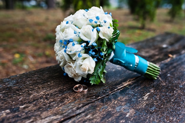Bukiet ślubny z białą różą i turkusową wstążką na drewnianej ławce