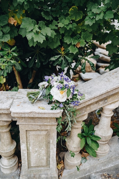 Bukiet ślubny z białych róż gałęzie drzewa eukaliptusowego i delikatne niebieskie kwiaty na balustradzie