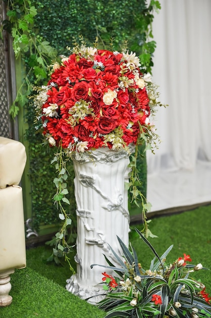 bukiet ślubny z czerwonych róż w wazonie na zielonej trawie