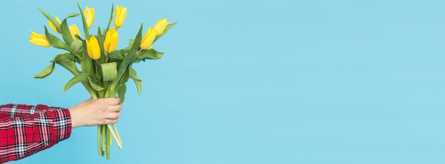 Bukiet Transparentu żółtych Tulipanów W Kobiecej Dłoni Na Niebieskim Tle Z Miejscem Na Kopię I Miejscem Na Adve