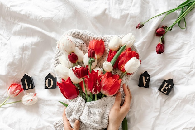 Bukiet tulipanów dekoracyjne słowo miłość w widoku z góry białego łóżka