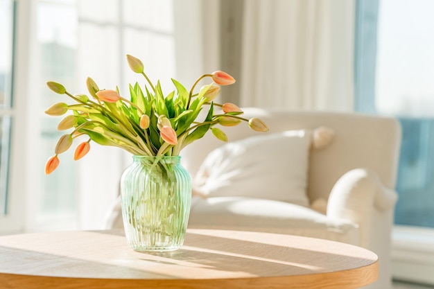 Bukiet tulipanów w pięknym wazonie w domu w jasnym nowoczesnym wnętrzu na drewnianym stole