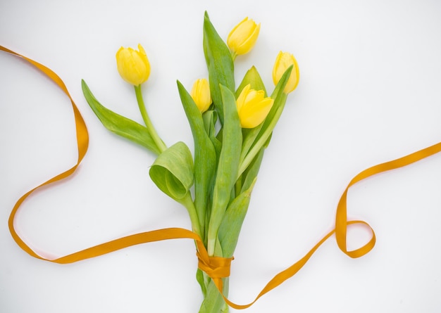 Bukiet żółtych tulipanów wiosna z czerwoną wstążką