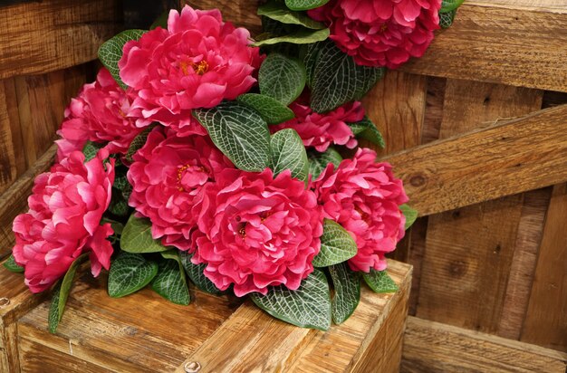 Bukiet żywe różowe kwiaty sztuczne na drewnianych skrzyniach