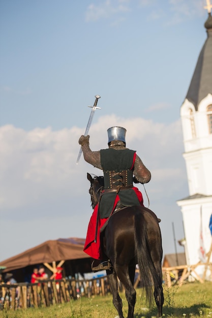 Zdjęcie bulgar, federacja rosyjska - sierpień 2018 - mężczyzna w żelaznej zbroi siedzi na koniu z podniesioną ręką, która trzyma miecz przed walką, z bliska