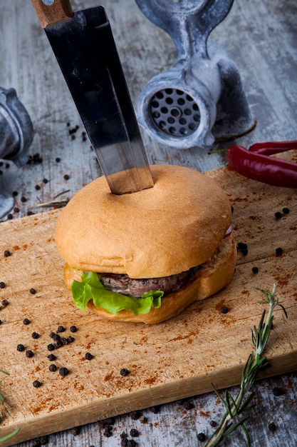 burger na desce z nożem i młynkiem z pieprzem