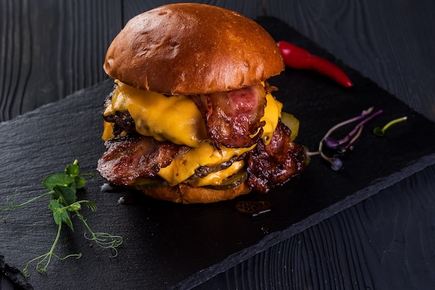 Burger. Podwójny kotlet, podwójny ser cheddar, bekon, cebula smażona, pikle, sos i bułka rzemieślnicza.