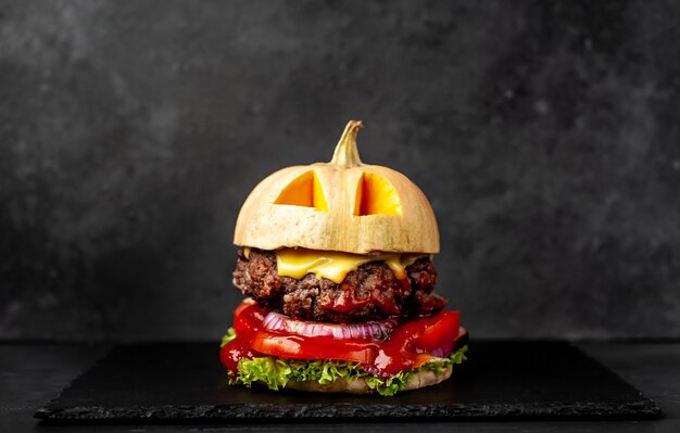 burger w kształcie dyni na wakacje Halloween na kamiennej ścianie