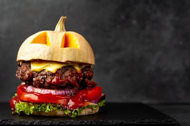 burger w kształcie dyni na wakacje Halloween na kamiennej ścianie