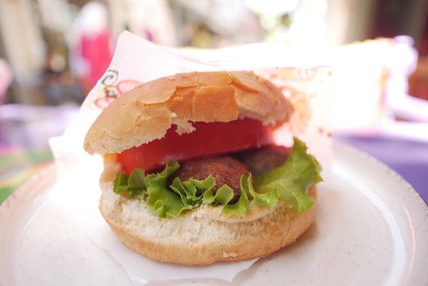burger wołowy z papierem na talerzu kawiarnia na świeżym powietrzu je jedzenie na ulicy koncepcja