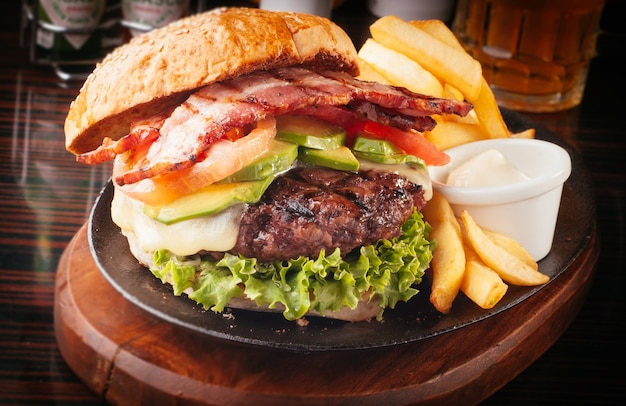 Burger z frytkami na talerzu na desce do cięcia