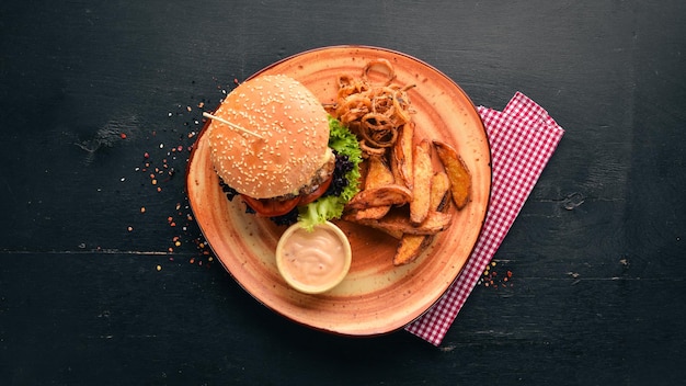 Burger z pomidorami mięsnymi cebulowymi i pieczonymi ziemniakami Na starym tle Darmowe miejsce na kopię Widok z góry