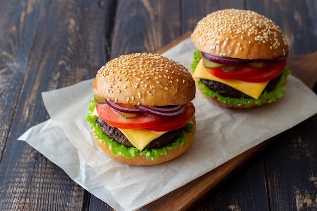 Burgery z kotletem, pomidorem, sałatą, ogórkiem, cebulą i serem. Kuchnia amerykańska. Fast food. Cheeseburger.