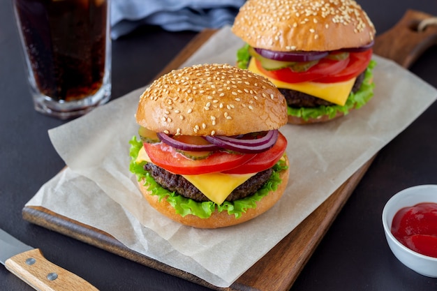 Burgery z kotletem, pomidorem, sałatą, ogórkiem, cebulą i serem. Kuchnia amerykańska. Fast food. Cheeseburger.