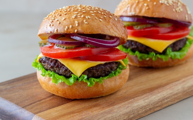 Burgery z kotletem, pomidorem, sałatą, ogórkiem, cebulą i serem. Kuchnia amerykańska. Fast food. Cheeseburger.