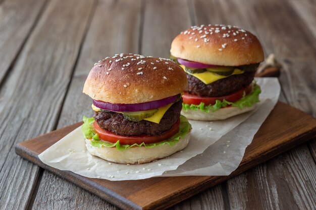 Burgery z mięsem, pomidorem, ogórkiem, serem i cebulą. Kuchnia amerykańska. Fast food.