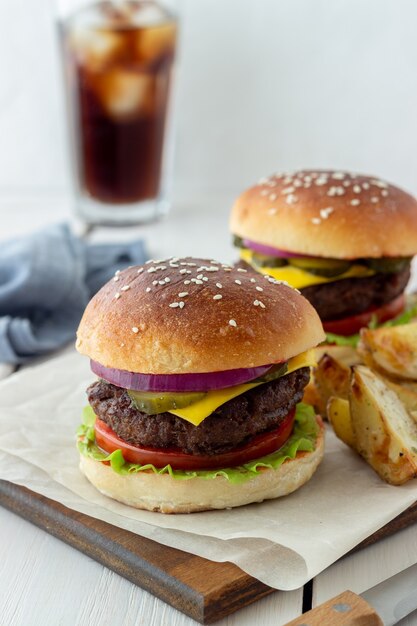 Burgery z mięsem, pomidorem, ogórkiem, serem i cebulą. Kuchnia amerykańska. Fast food.