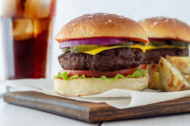 Burgery z mięsem, pomidorem, ogórkiem, serem i cebulą. Kuchnia amerykańska. Fast food.