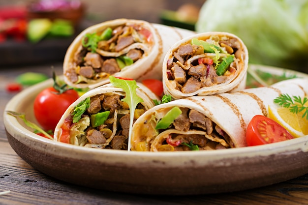 Burritos zawija wołowinę i warzywa na drewnie. Burrito wołowe, meksykańskie jedzenie. Tło zdrowej żywności. Kuchnia meksykańska.