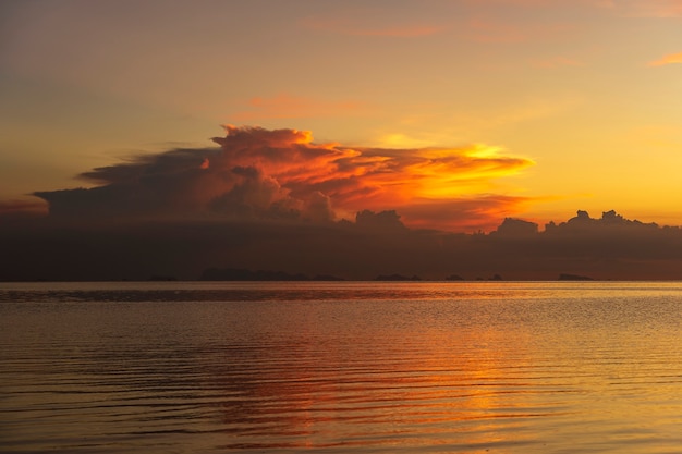 Burzowe chmury podczas zachodu słońca. Kolorowy zachód słońca nad spokojną wodą morską w pobliżu tropikalnej plaży. Koncepcja wakacji letnich. Wyspa Koh Phangan, Tajlandia