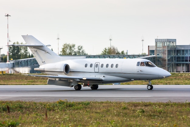 Business Jet na pasie startowym przed terminalem lotniska