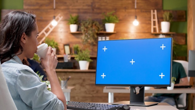 Businesswoman patrząc na makiety komputera z kluczem chroma zielonym ekranie z izolowanym wyświetlaczem analizującym strategię marketingową w biurze firmy startowej. Przedsiębiorca pracujący przy projekcie biznesowym