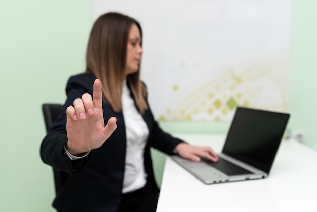 Businesswoman wpisuje ostatnie aktualizacje na klawiaturze na laptopie na biurku i wskazuje ważne pomysły jednym palcem Kobieta w biurze pisze spóźnione wiadomości na komputerze