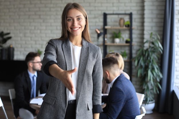 Businesswoman z otwartą dłonią gotowy do uścisku dłoni w biurze.