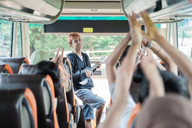 Busker używający ukulele i pasażerowie autobusów śpiewają i klaszczą w dłonie podczas podróży