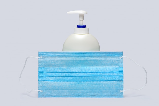 Butelka balsamu, środka odkażającego lub mydła w płynie i maska ochronna na jasnoszarym tle