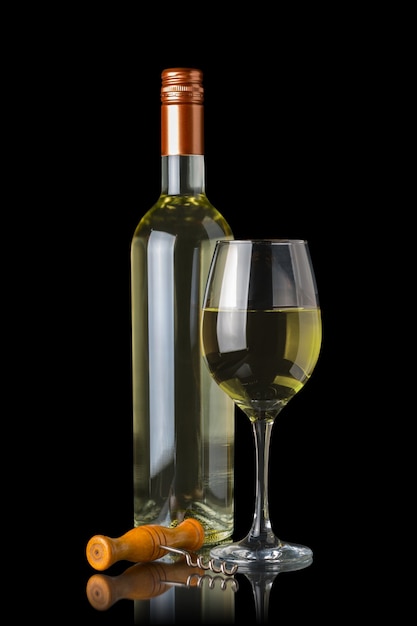 Butelka białego wina obok kieliszka i korkociąg na białym tle na czarnej ścianie