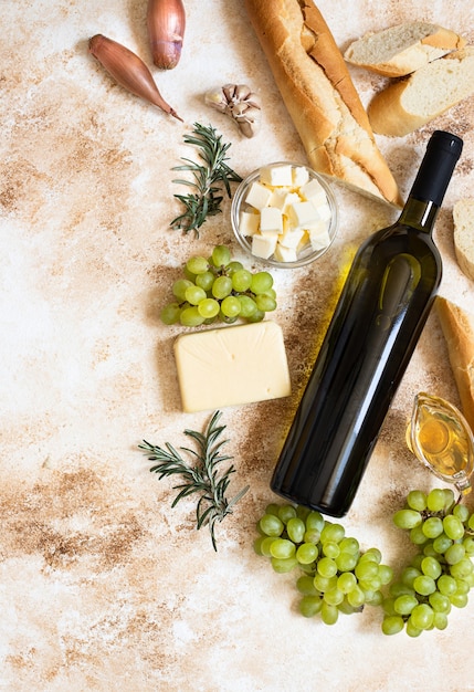 butelka białego wina, winogron, sera, masła i bagietki z widokiem z góry