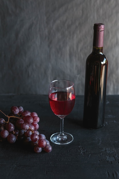 Butelka czerwonego wina i wina z winogronami na czarno