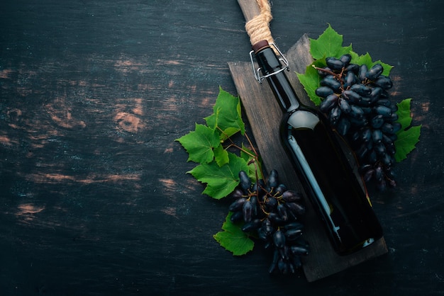 Butelka czerwonego wina na czarnym drewnianym tle Winogrono Wolne miejsce na tekst Widok z góry