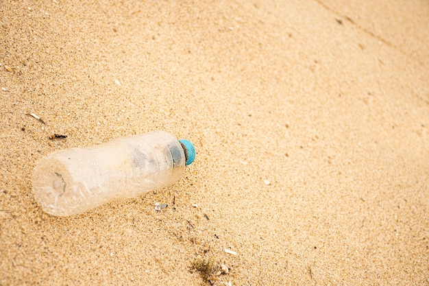 Butelka dla zwierząt wyrzucona na piasek na plaży Śmieci i zanieczyszczenie przez człowieka na plażach przyroda
