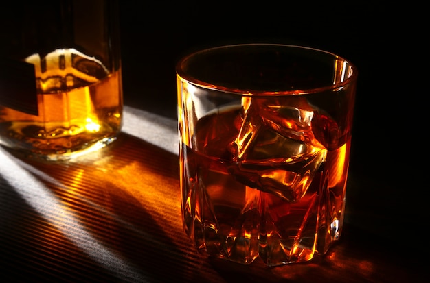 Butelka I Kieliszek Whisky Lub Bourbon Z Lodem Na Stole Z Czarnego Kamienia.